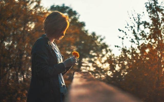 Femme tenant une fleur, émotions, erreurs en amour, amour fragile