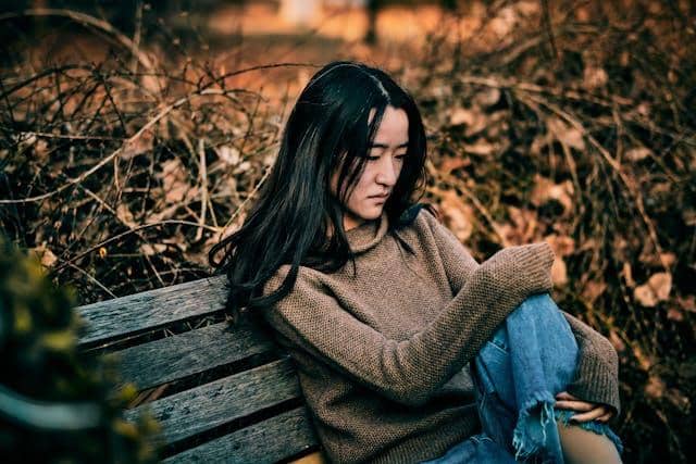 Femme assise sur un banc, automne, introspection après une rupture